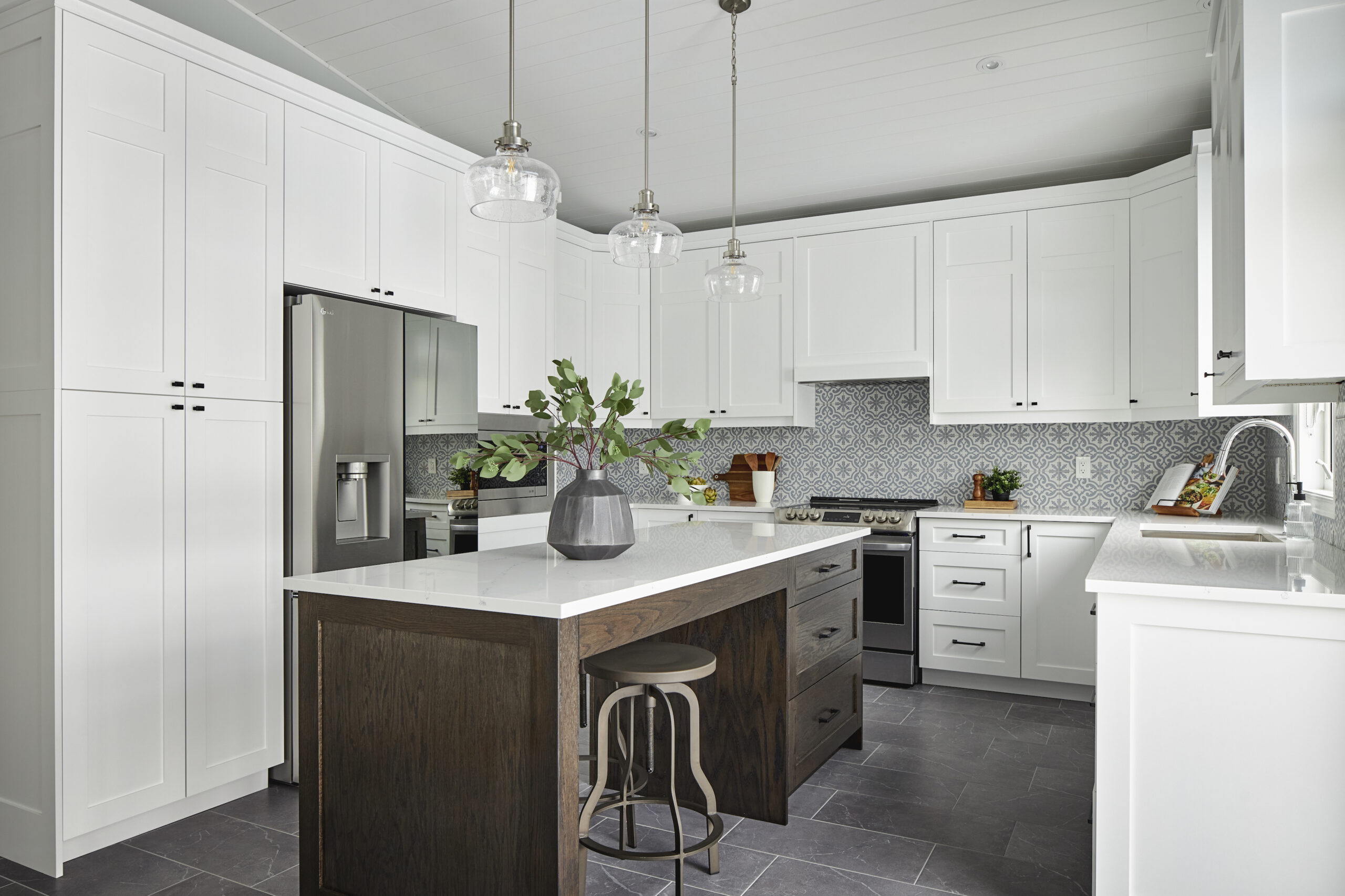 Designer kitchen renovation with white cabinetry and patterned backsplash. A dark island in the centre of the kitchen brings contrast to the space.