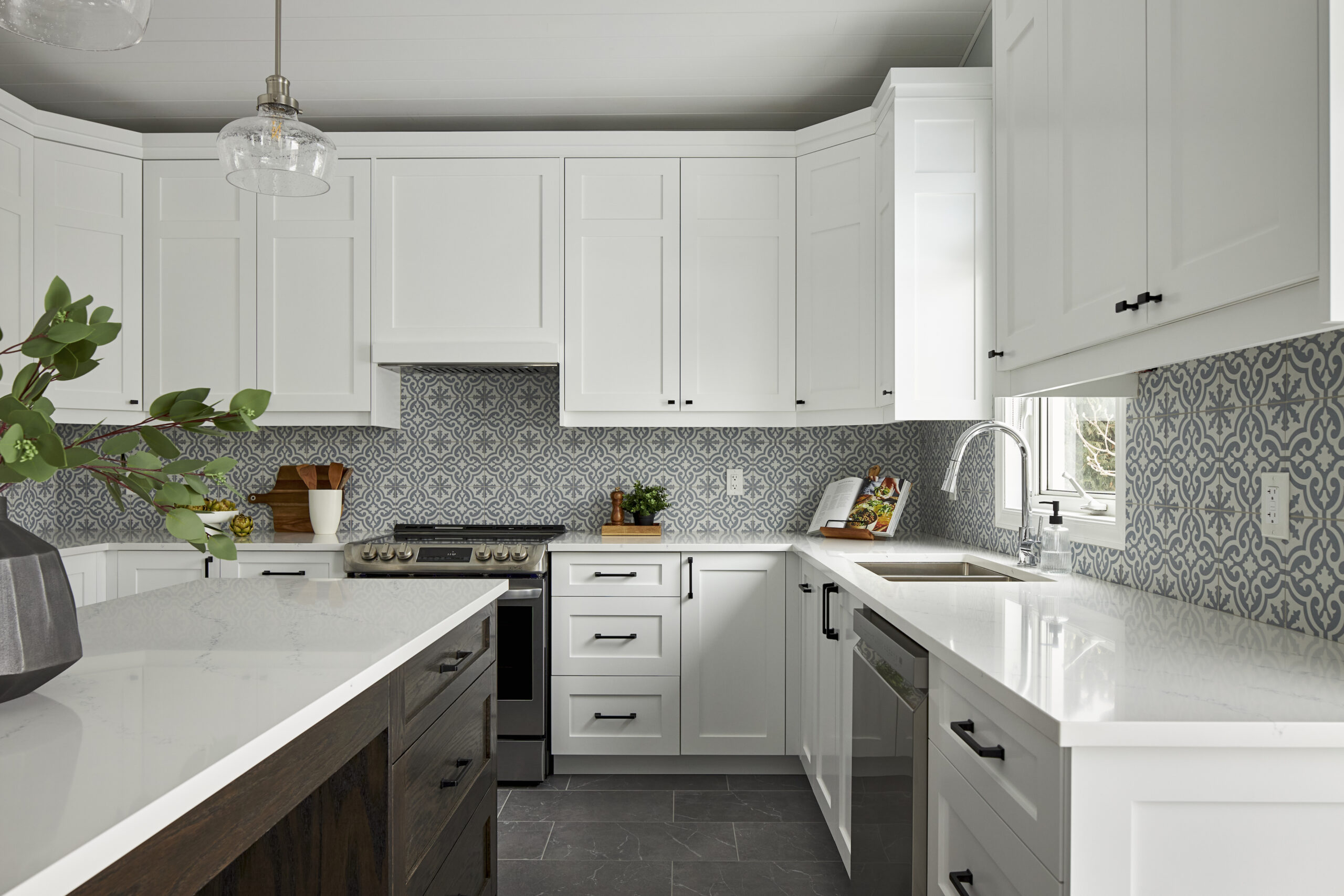 Designer kitchen renovation with white cabinetry and patterned backsplash.