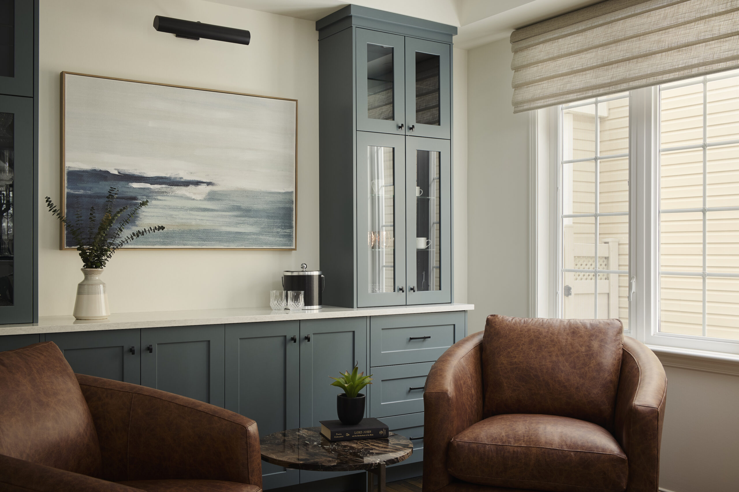Beautiful custom blue cabinets serve as a bar area in this clients dining room. There are two tall cabinets surrounding a stunning painting.