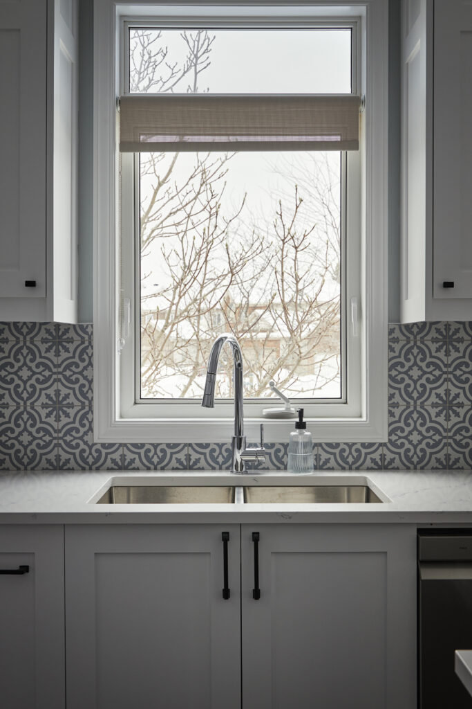 Designer kitchen with white cabinetry and patterned backsplash.
