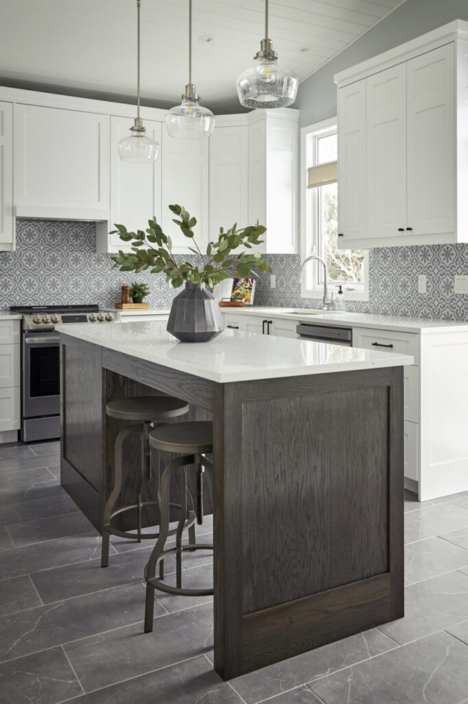 Designer kitchen with white cabinetry and patterned backsplash. A dark wood island in the middle of the kitchen brings contrast to the space.