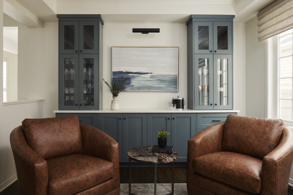 Stunning custom blue cabinetry stores glassware and surrounds a custom painting.